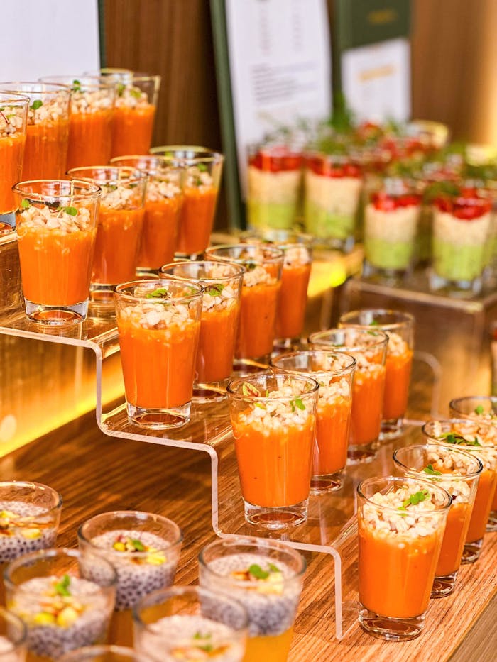 Luxurious appetizer selection with vibrant tomato gazpacho shots in a Dubai event setting.